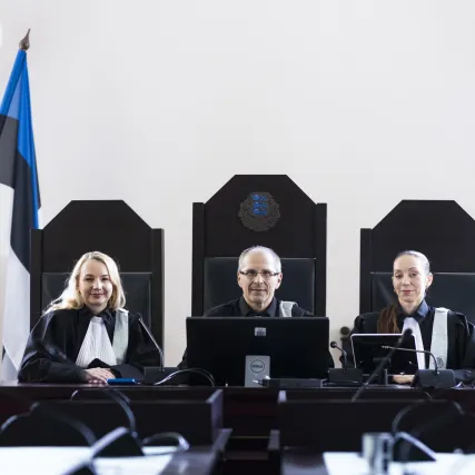 Kolm talaaris kohtunikku istuvad laua taga.