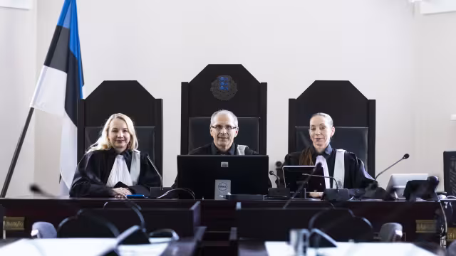 Kolm talaaris kohtunikku istuvad laua taga.