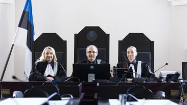 Kolm talaaris kohtunikku istuvad laua taga.